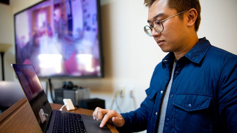 Enton Lok uses immersive media to help people virtually embody volunteering. Student using their laptop.